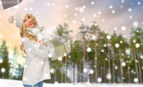 Image of happy woman in hat and scarf over winter forest