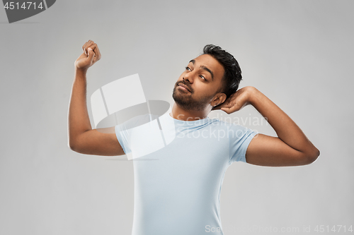 Image of indian man stretching over grey background