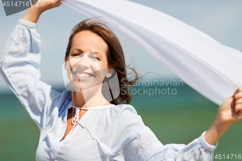 Image of happy woman with shawl waving in wind on beach