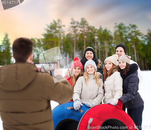 Image of friends with snow tubes taking photo by tablet pc
