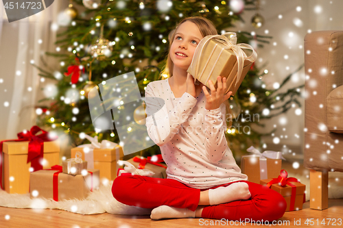 Image of smiling girl with christmas gift at home