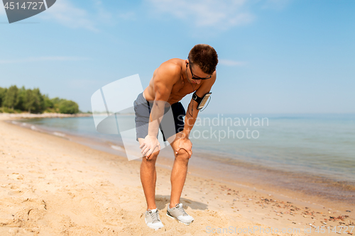 Image of male runner with earphones and arm band on beach