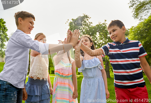 Image of group of happy kids making high five outdoors