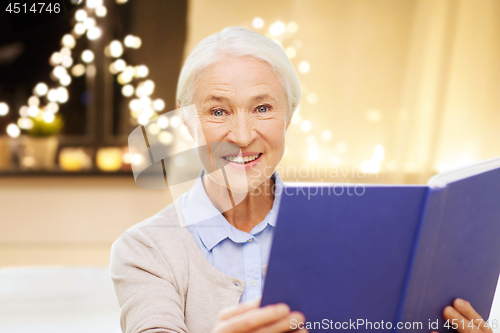 Image of smiling senior woman reading book on christmas