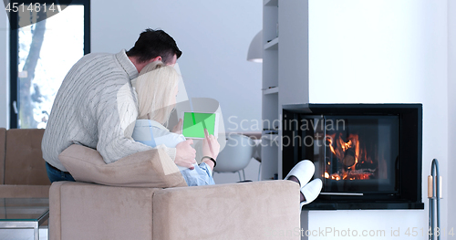 Image of couple relaxing at  home with tablet computers
