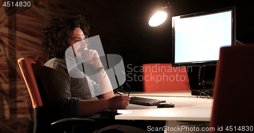 Image of man working on computer in dark office