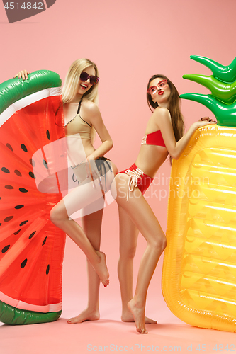 Image of Cute girls in swimsuits posing at studio. Summer portrait caucasian teenagers on pink background.