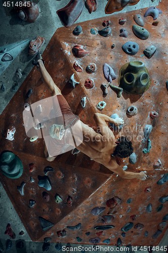 Image of Free climber young man climbing artificial boulder indoors