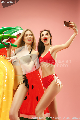 Image of Cute girls in swimsuits posing at studio. Summer portrait caucasian teenagers on pink background.