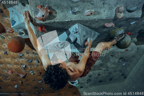 Image of Free climber young man climbing artificial boulder indoors