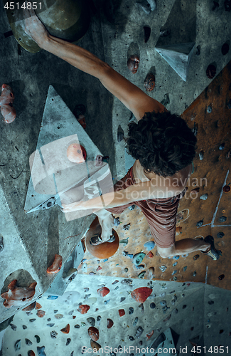 Image of Free climber young man climbing artificial boulder indoors