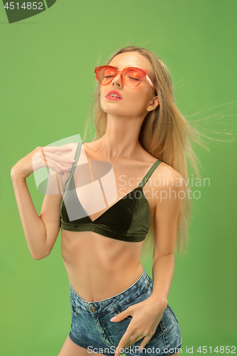Image of Cute girl in swimsuit posing at studio. Summer portrait caucasian teenager on green background.