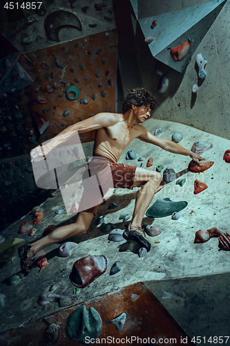 Image of Free climber young man climbing artificial boulder indoors