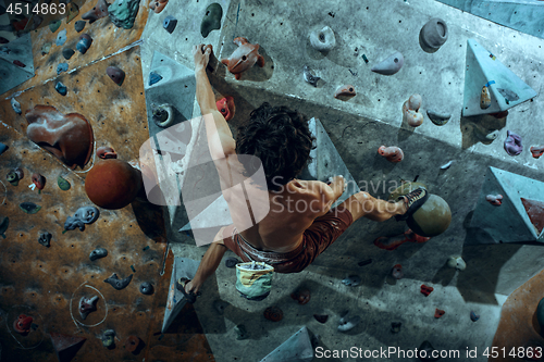 Image of Free climber young man climbing artificial boulder indoors