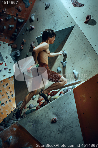 Image of Free climber young man climbing artificial boulder indoors