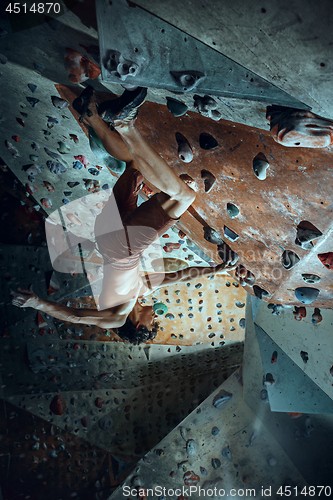 Image of Free climber young man climbing artificial boulder indoors