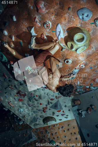 Image of Free climber young man climbing artificial boulder indoors