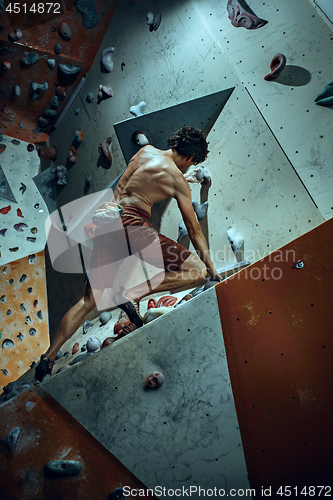 Image of Free climber young man climbing artificial boulder indoors