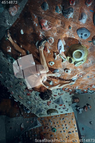 Image of Free climber young man climbing artificial boulder indoors