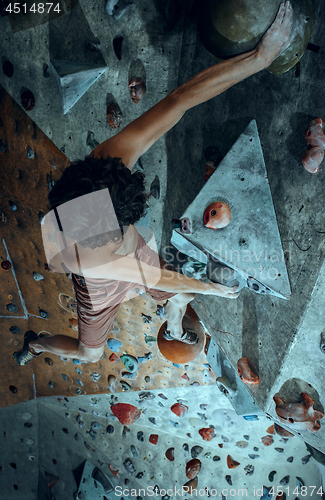 Image of Free climber young man climbing artificial boulder indoors