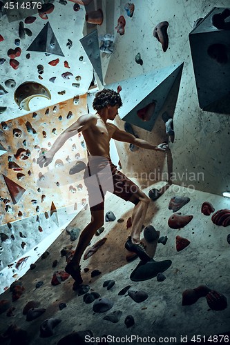 Image of Free climber young man climbing artificial boulder indoors