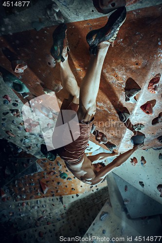 Image of Free climber young man climbing artificial boulder indoors