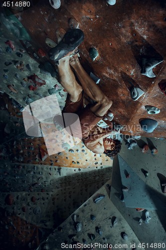 Image of Free climber young man climbing artificial boulder indoors