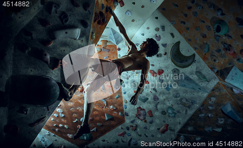 Image of Free climber young man climbing artificial boulder indoors