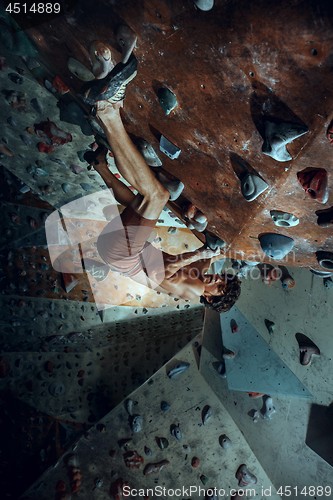 Image of Free climber young man climbing artificial boulder indoors