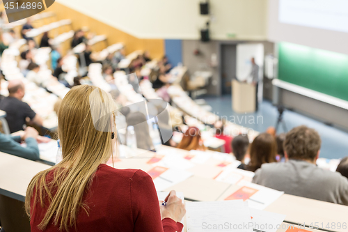 Image of Audience in the lecture hall. Female student making notes.