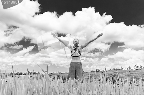 Image of Relaxed healthy sporty woman, arms rised to the sky, enjoying pure nature at beautiful green rice fields on Bali.