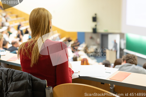 Image of Audience in the lecture hall. Female student making notes.