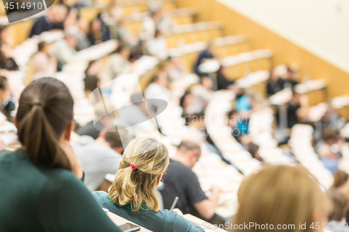 Image of Audience in the lecture hall. Female student making notes.