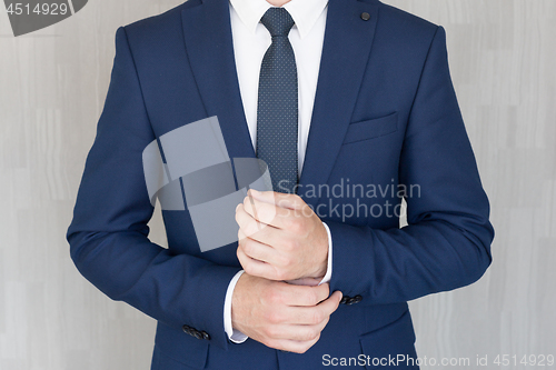 Image of Torso of anonymous businessman wearing beautiful fashionable classic navy blue suit against grey backgound.