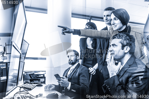 Image of Successful business team looking at trade data on computer screens in corporate office.