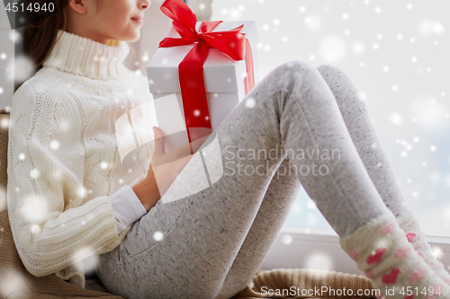 Image of girl with christmas gift sitting on sill at home