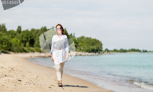 Image of happy smiling woman walking along summer beach