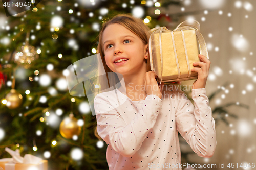 Image of smiling girl with christmas gift at home