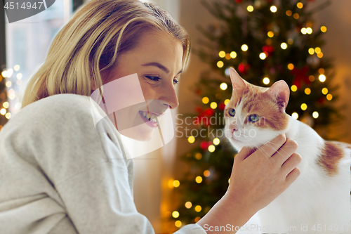 Image of happy young woman with cat at home on christmas