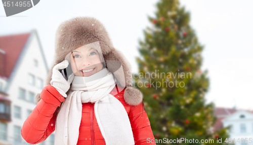 Image of woman calling on smartphone over christmas tree
