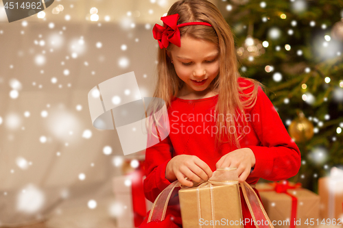 Image of smiling girl with christmas gift at home