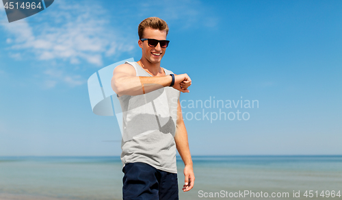 Image of happy man with fitness tracker on summer beach