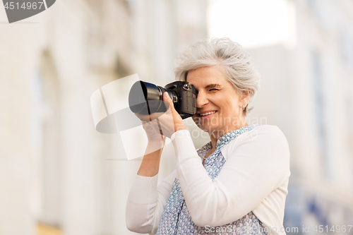 Image of senior woman photographing by digital camera