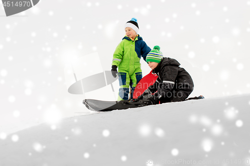 Image of kids sliding on sleds down snow hill in winter