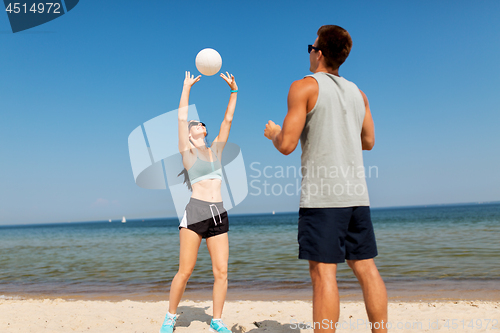 Image of happy couple playing volleyball on summer beach