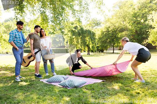 Image of friends arranging place for picnic at summer park