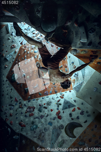 Image of Free climber young man climbing artificial boulder indoors