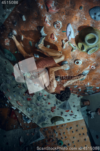 Image of Free climber young man climbing artificial boulder indoors