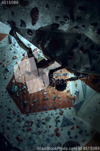 Image of Free climber young man climbing artificial boulder indoors