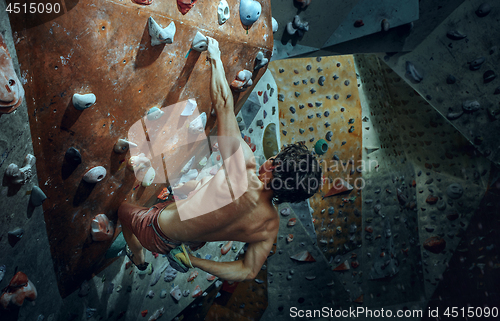 Image of Free climber young man climbing artificial boulder indoors